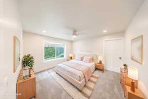 Spacious room featuring light gray carpeting, a large window, recessed lighting, a ceiling fan, and a three-panel door