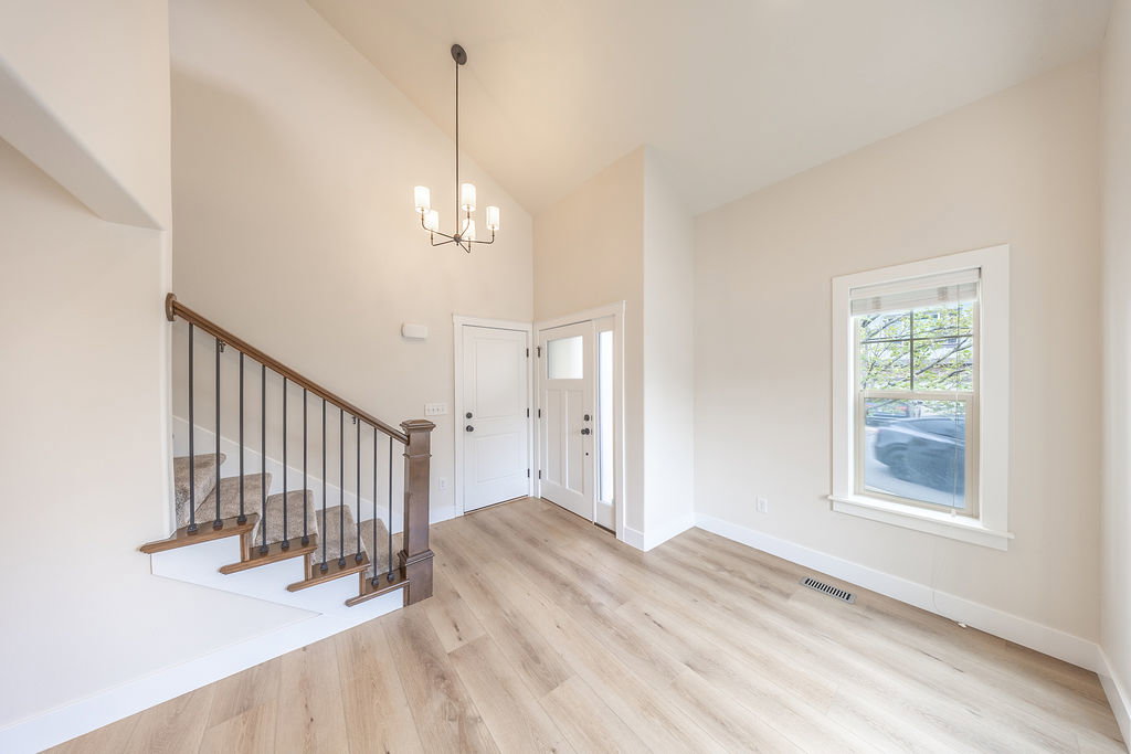 Entryway featuring light wood-finish flooring, a contemporary chandelier, and a white paneled door with sidelight