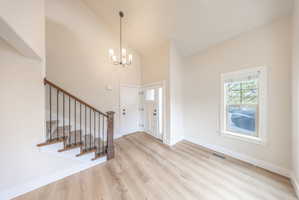Entryway featuring light wood-finish flooring, a contemporary chandelier, and a white paneled door with sidelight