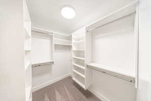 Walk-in closet featuring white built-in shelving, multiple hanging rods, and recessed lighting