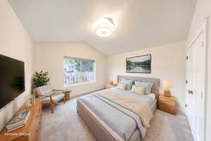Spacious room featuring a vaulted ceiling and a large window