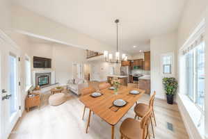 Open-concept living space featuring wood-finish flooring, a contemporary fireplace, and a dining area with a modern chandelier