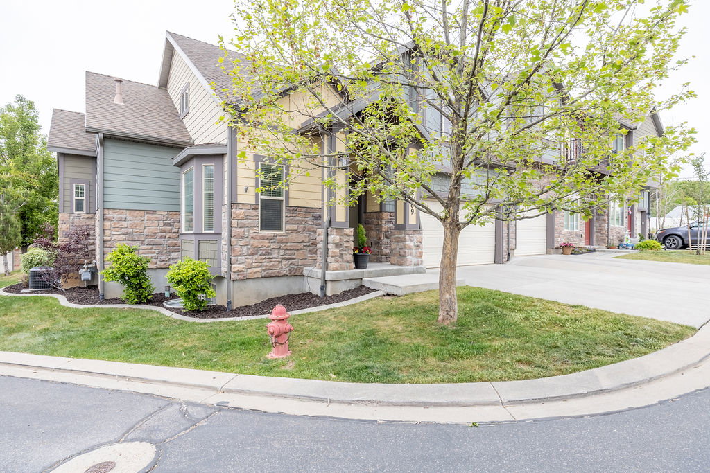Multi-level exterior featuring stone veneer, horizontal siding, a bay window, and a concrete driveway