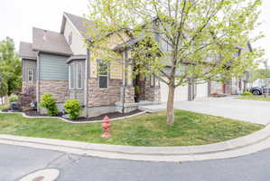 Multi-level exterior featuring stone veneer, horizontal siding, a bay window, and a concrete driveway