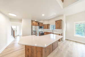 Spacious kitchen featuring a large island with a white countertop, wood cabinetry, and stainless steel appliances