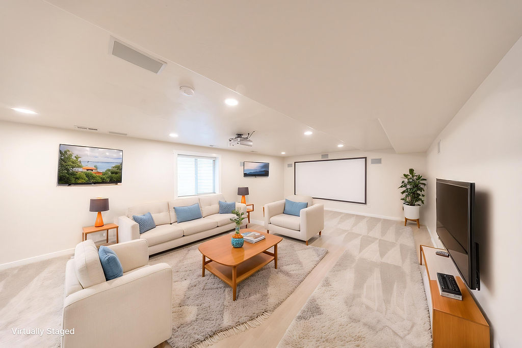 Spacious entertainment area featuring recessed lighting, a large projection screen, and a wall-mounted flat-screen television