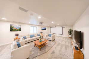 Spacious entertainment area featuring recessed lighting, a large projection screen, and a wall-mounted flat-screen television