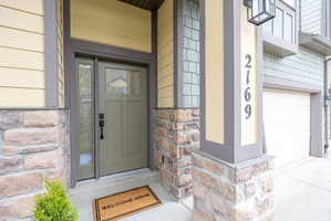 Exterior entry with a paneled door and sidelight, complemented by horizontal siding and stone veneer accents