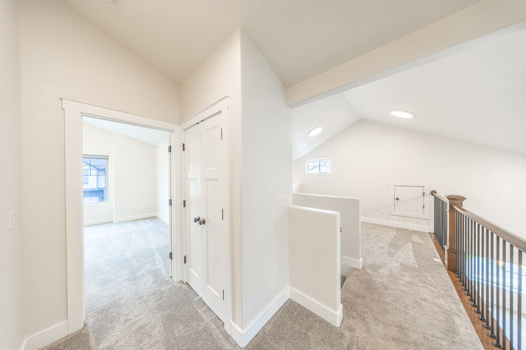Carpeted hallway featuring a vaulted ceiling, recessed lighting, and a white paneled door