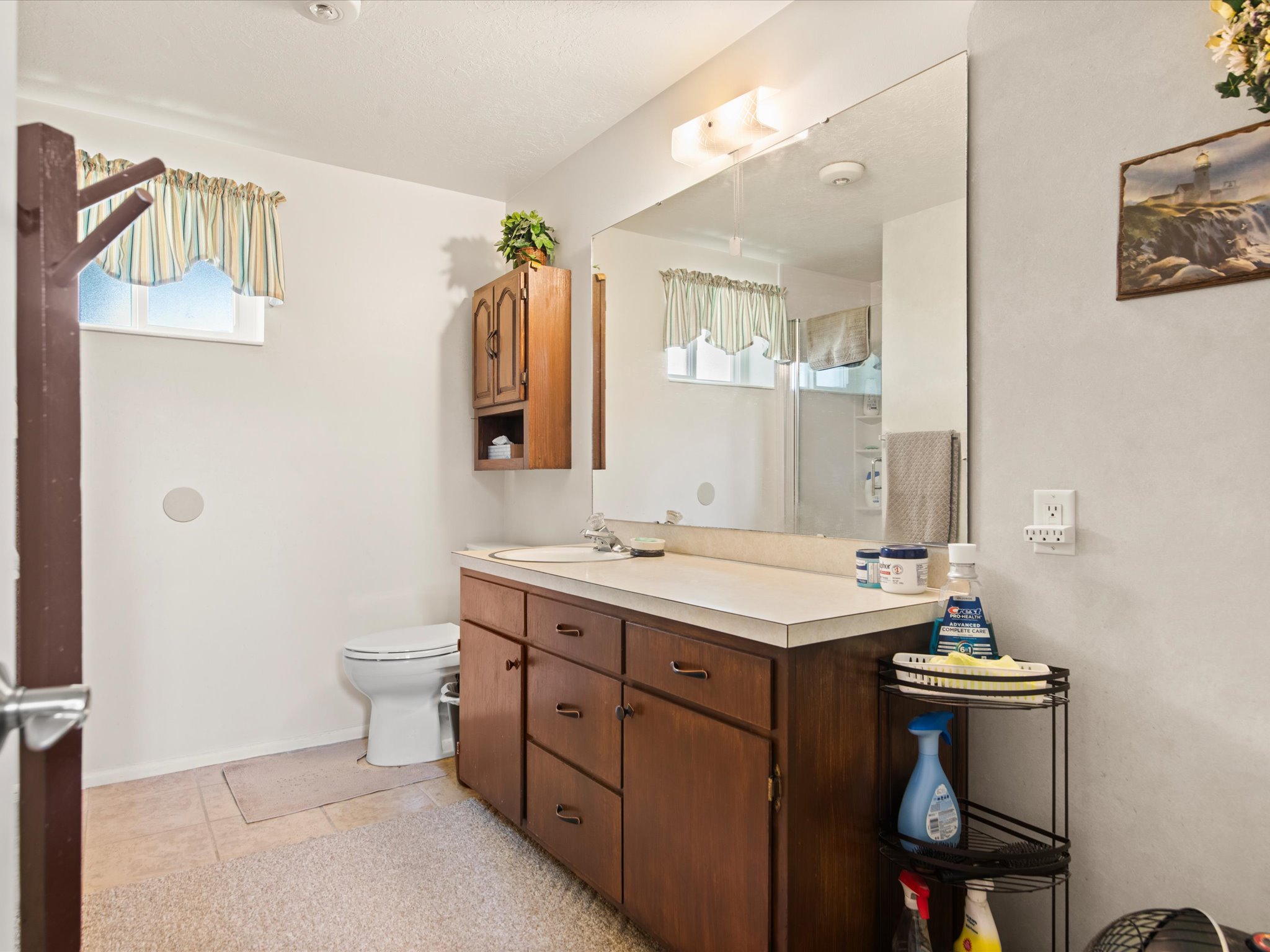 Bathroom vanity featuring a laminate countertop, integrated sink, and wood-finish cabinetry