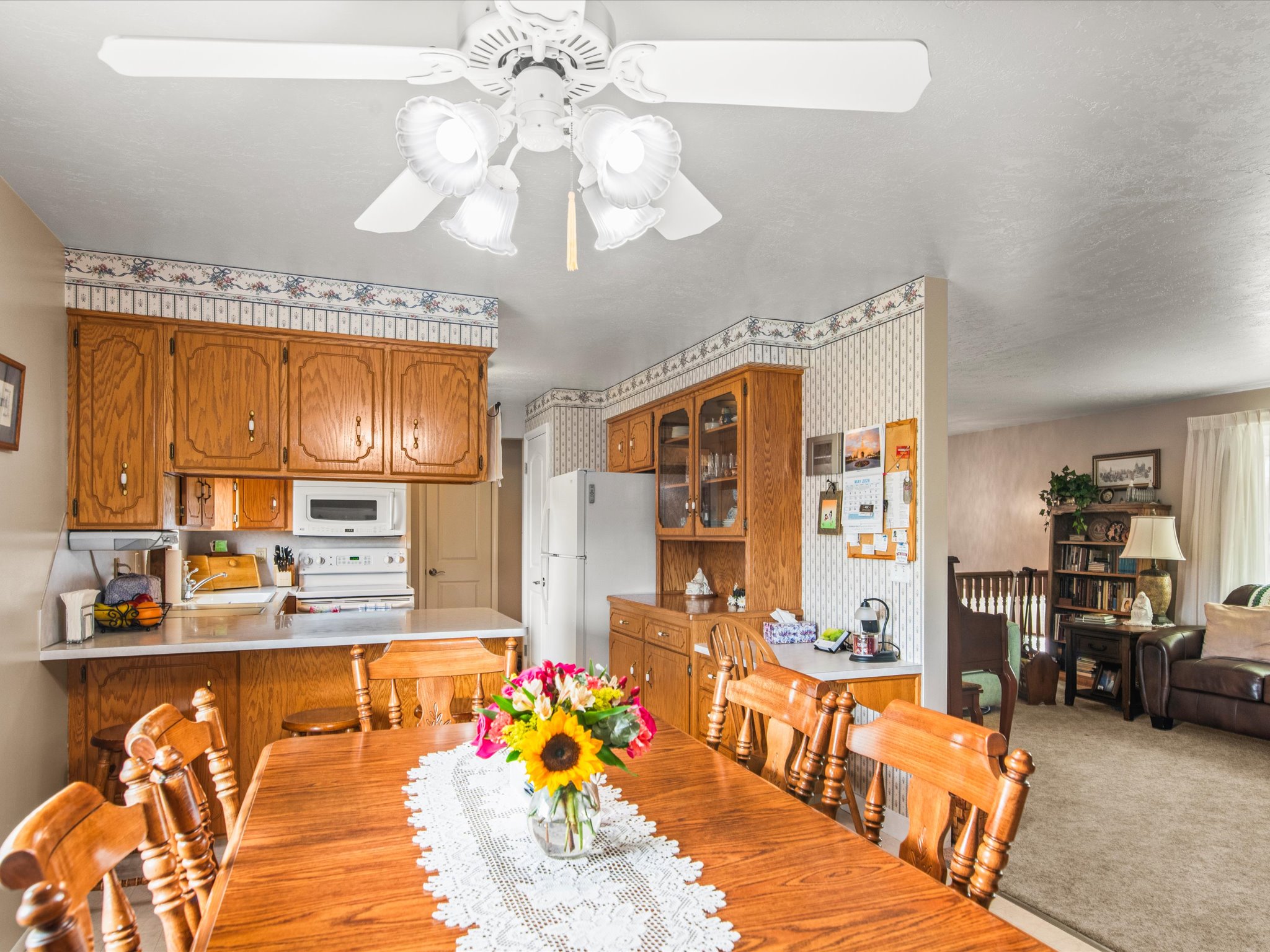 Dining area featuring a wood-finish table with seating for six, illuminated by a ceiling fan with integrated lighting