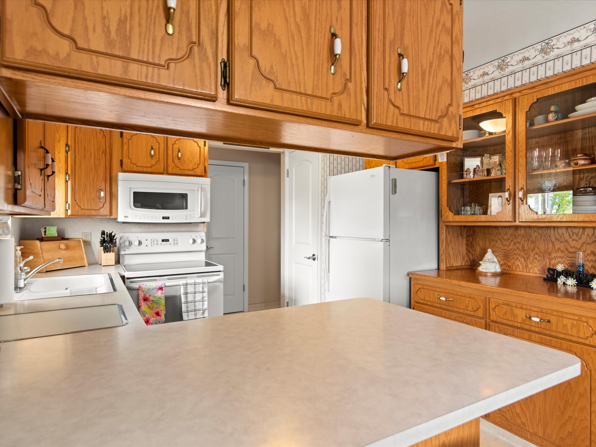 Kitchen featuring wood cabinetry, white appliances, a built-in microwave, and a double-basin sink