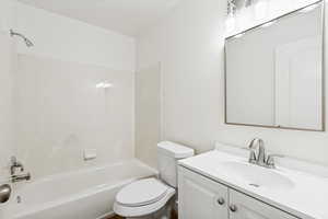 Bathroom featuring a vanity with a white countertop and integrated sink, brushed nickel faucet, and a wall-mounted mirror with a contemporary light fixture