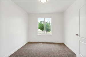 Bright room featuring a large window, neutral carpeting, white trim, a flush mount ceiling light, and a white panel door with a metallic knob