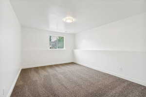 Spacious room featuring neutral carpet, white walls, and a single window offering natural light