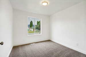 Room featuring neutral wall tones, gray textured carpet, and white baseboards