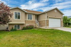 Split-level residence featuring a two-car garage, stucco exterior, and stone accent banding