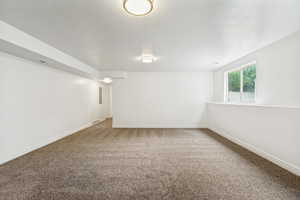 Spacious room featuring neutral carpeting, white walls, recessed window, and two ceiling-mounted light fixtures