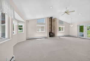 Spacious interior featuring a wood-burning stove with a tiled surround, vaulted ceilings, and recessed lighting