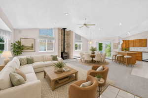 Virtual staging included to showcase room potential.  Vaulted ceiling living space featuring a wood stove with tile surround, bay window, and light wood-finish flooring