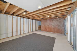 Unfinished basement space featuring exposed wood joists, recessed lighting, and framed walls
