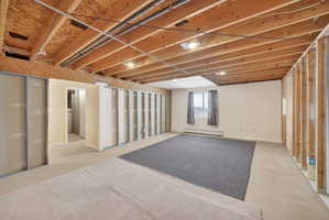 Unfinished basement with exposed wood joist ceiling, recessed lighting, and partial framing for future development