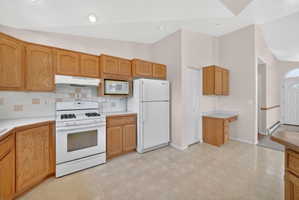 Kitchen featuring wood-finish cabinetry and white appliances