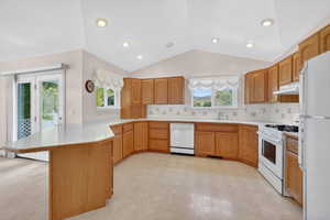 Kitchen featuring extensive wood cabinetry, white countertops, recessed lighting, and a vaulted ceiling