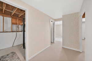 Unfinished basement area offering exposed ceiling joists and concrete flooring, with a tiled section visible