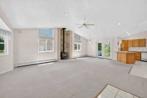 Spacious living area featuring vaulted ceilings, a wood-burning stove with a tiled surround, and multiple windows