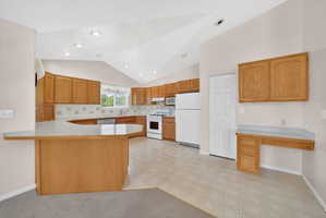 Kitchen with wood-finish cabinetry, light-colored countertops, and a built-in desk area