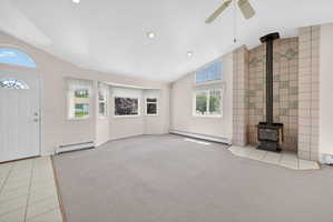Living area featuring a wood-burning stove with a tiled surround, vaulted ceilings, and recessed lighting