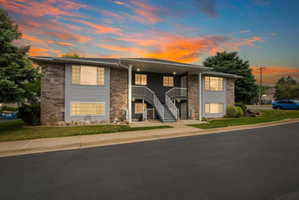 Multi-unit building featuring brick and siding exterior, multiple windows, and a prominent exterior staircase
