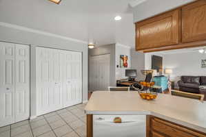 Kitchen peninsula with a light-toned countertop, integrated dishwasher, and wood-finish cabinetry