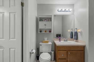 En suite 1/2 Bathroom featuring a wood-finish vanity with a light-toned countertop and sink