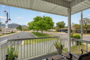 Covered balcony off primary bedroom with white railings and an overhead paneling