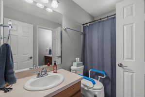 Bathroom featuring a single vanity with an integrated sink, a rectangular mirror, a three-bulb vanity light fixture, and a bathtub