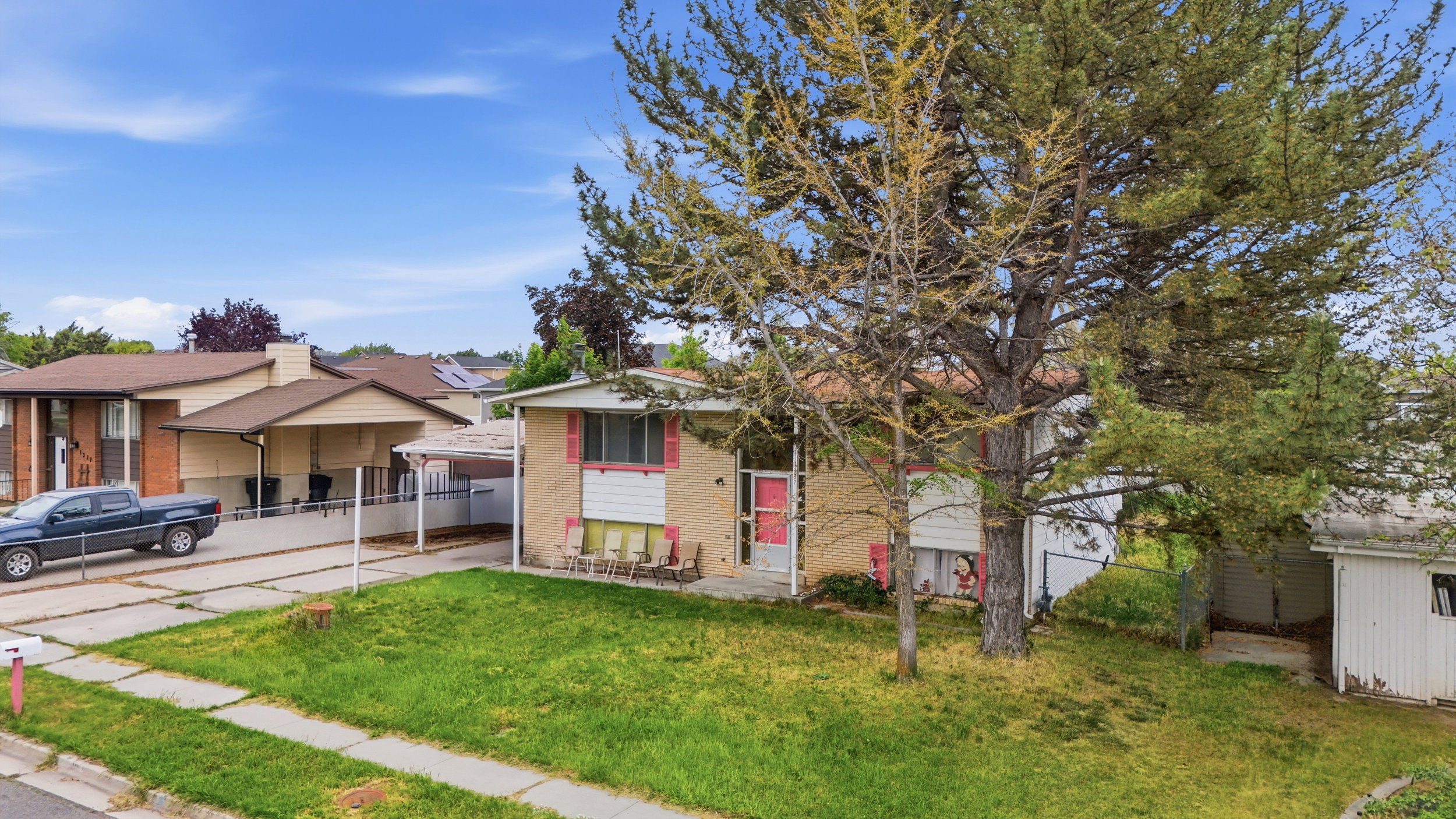 Split-level residence featuring a brick and siding exterior, an attached carport, and a mature front yard tree
