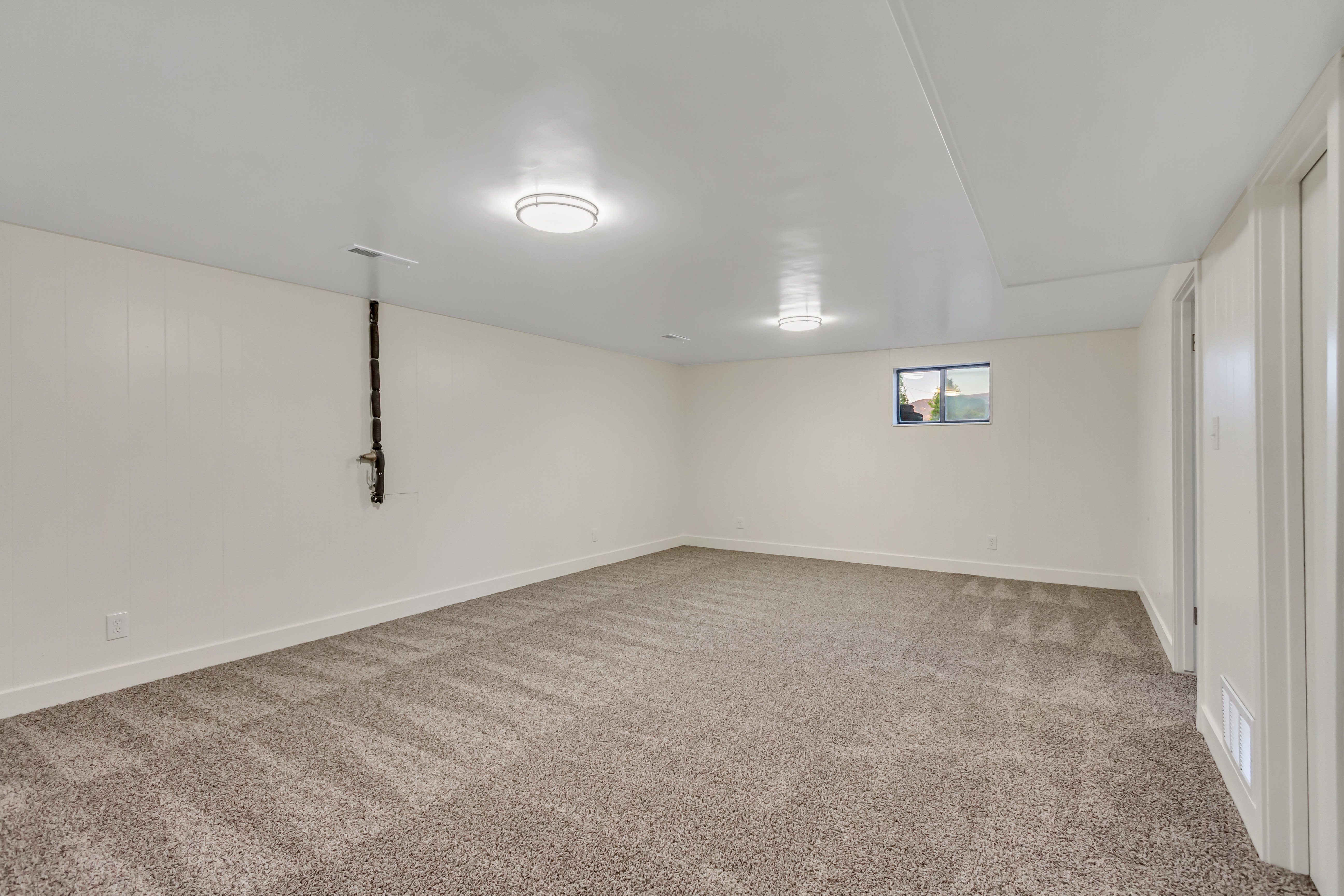 Spacious room featuring neutral-toned carpeting, white walls, and recessed lighting fixtures