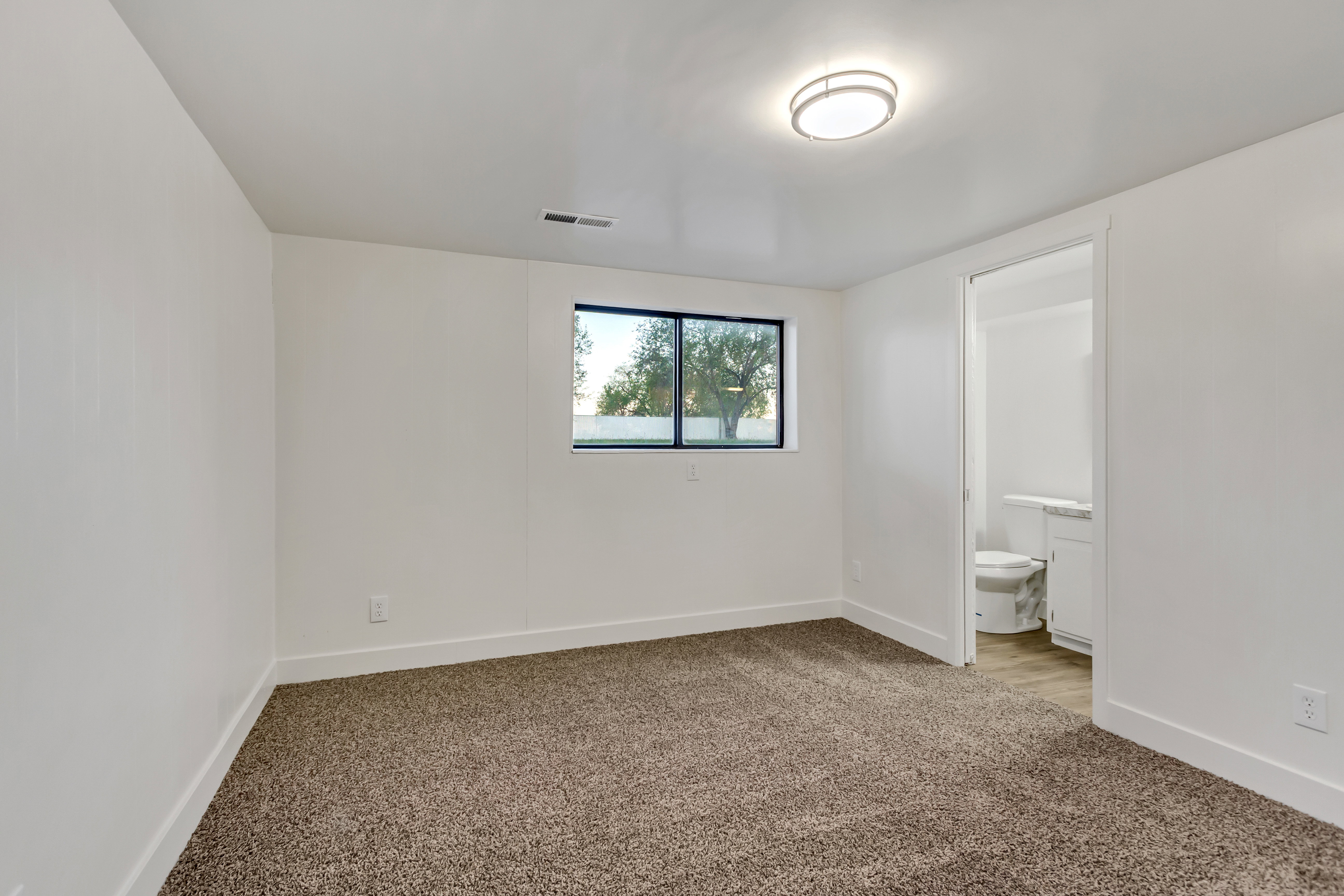 Carpeted room with white walls, a recessed window, and a flush-mount ceiling light