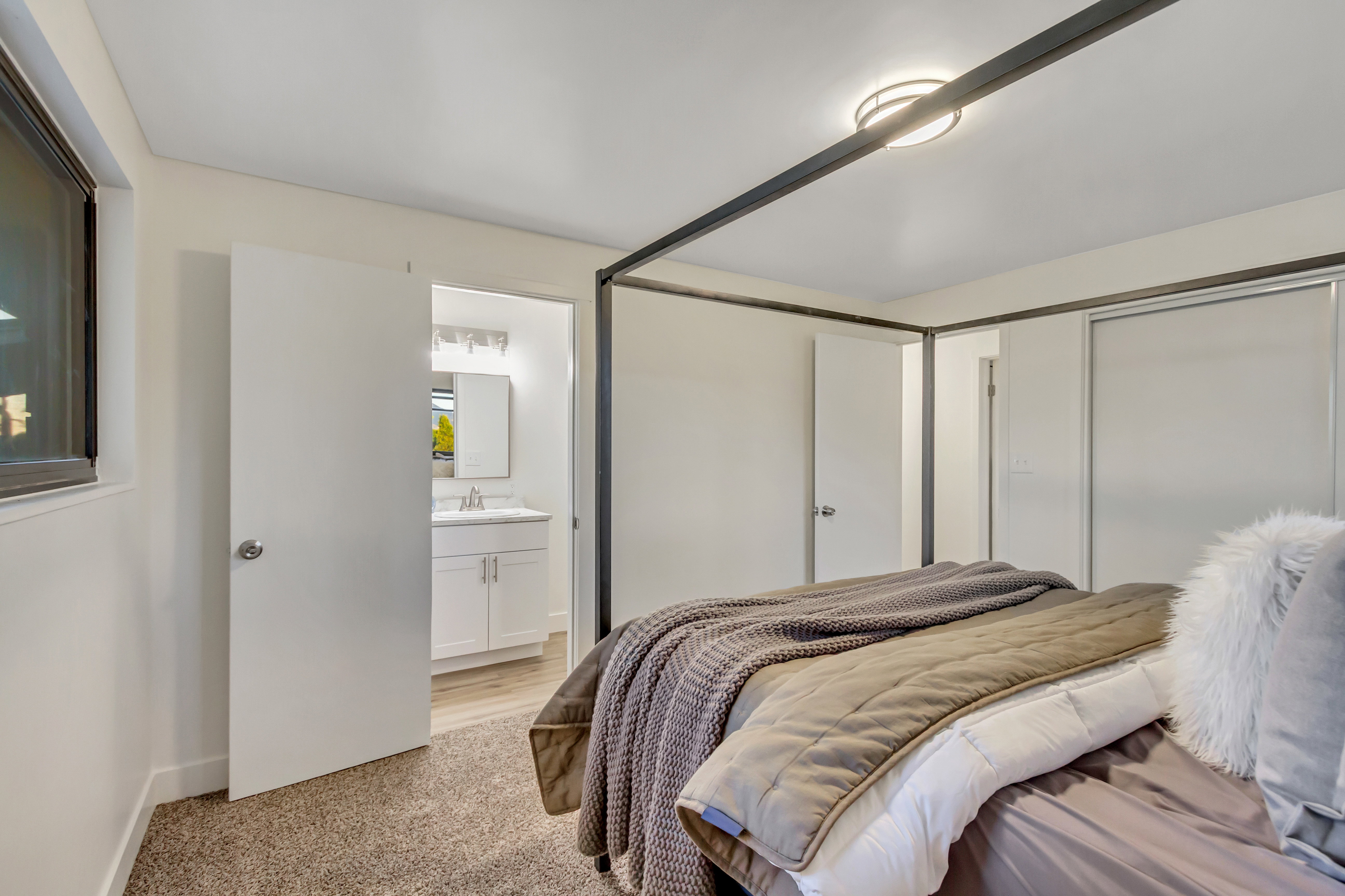 Carpeted bedroom featuring a window, ceiling-mounted light fixture, and a white sliding closet door