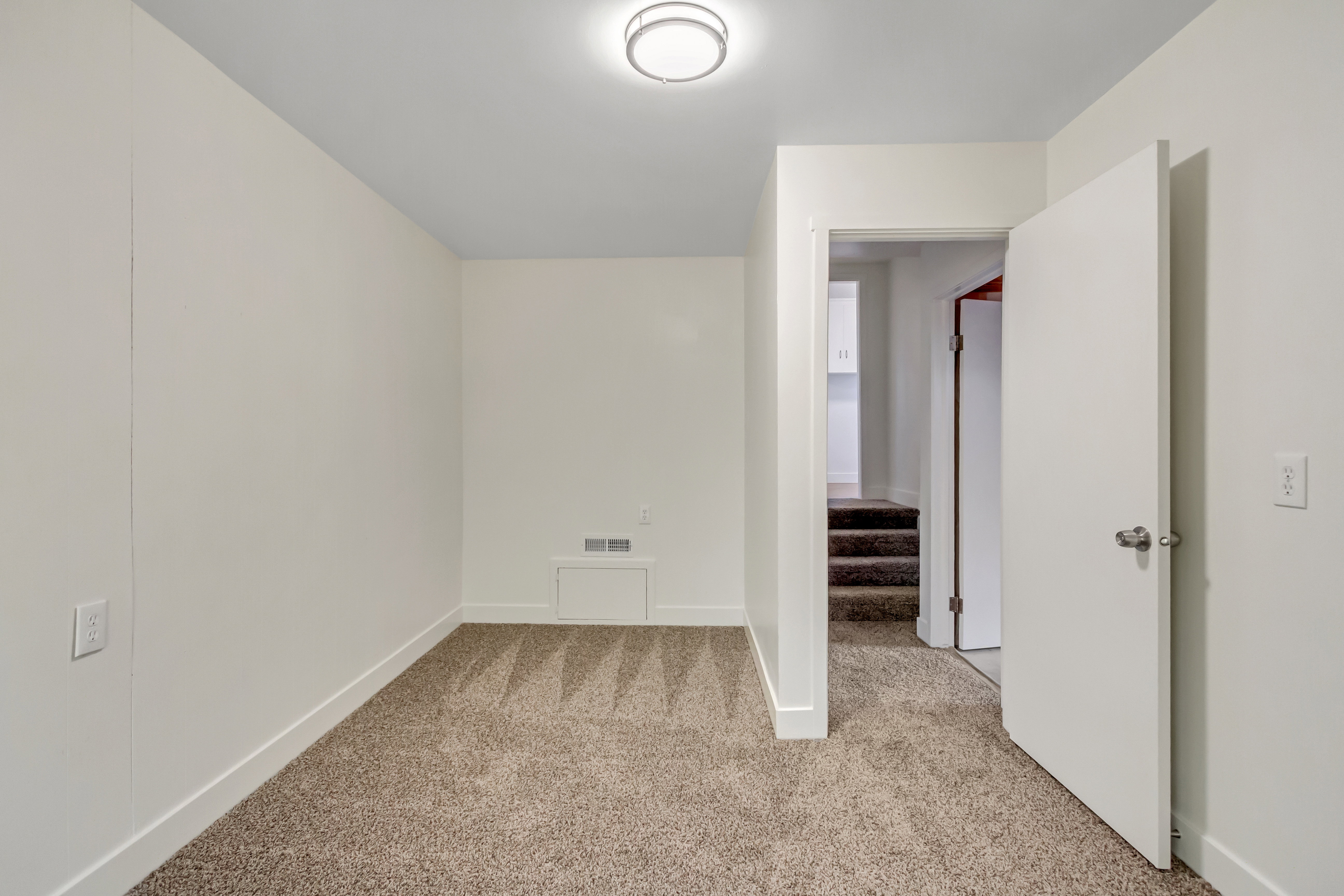 Carpeted room with white walls and a ceiling-mounted light fixture