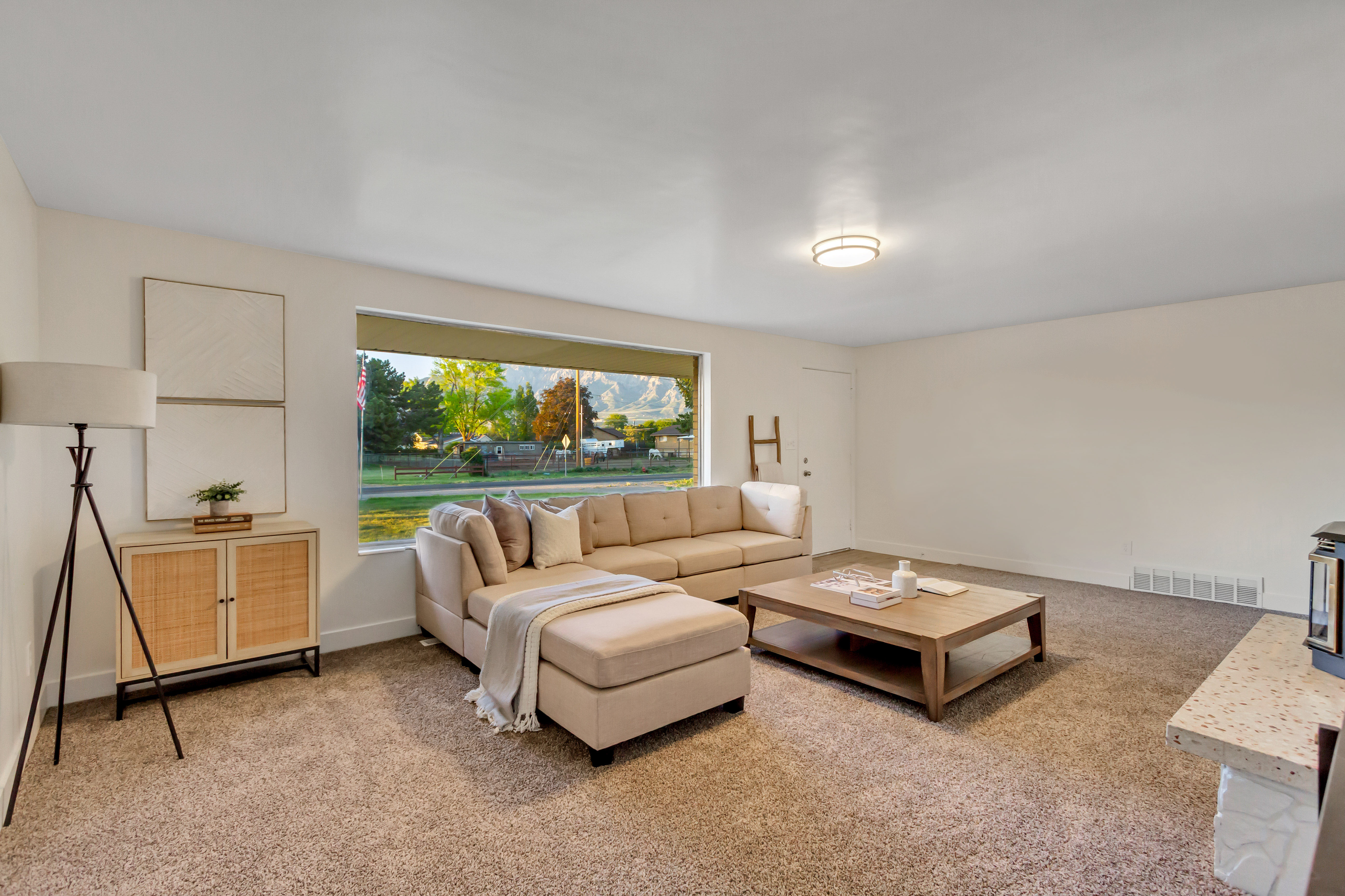 Spacious room featuring a large window, neutral carpeting, and light-colored walls
