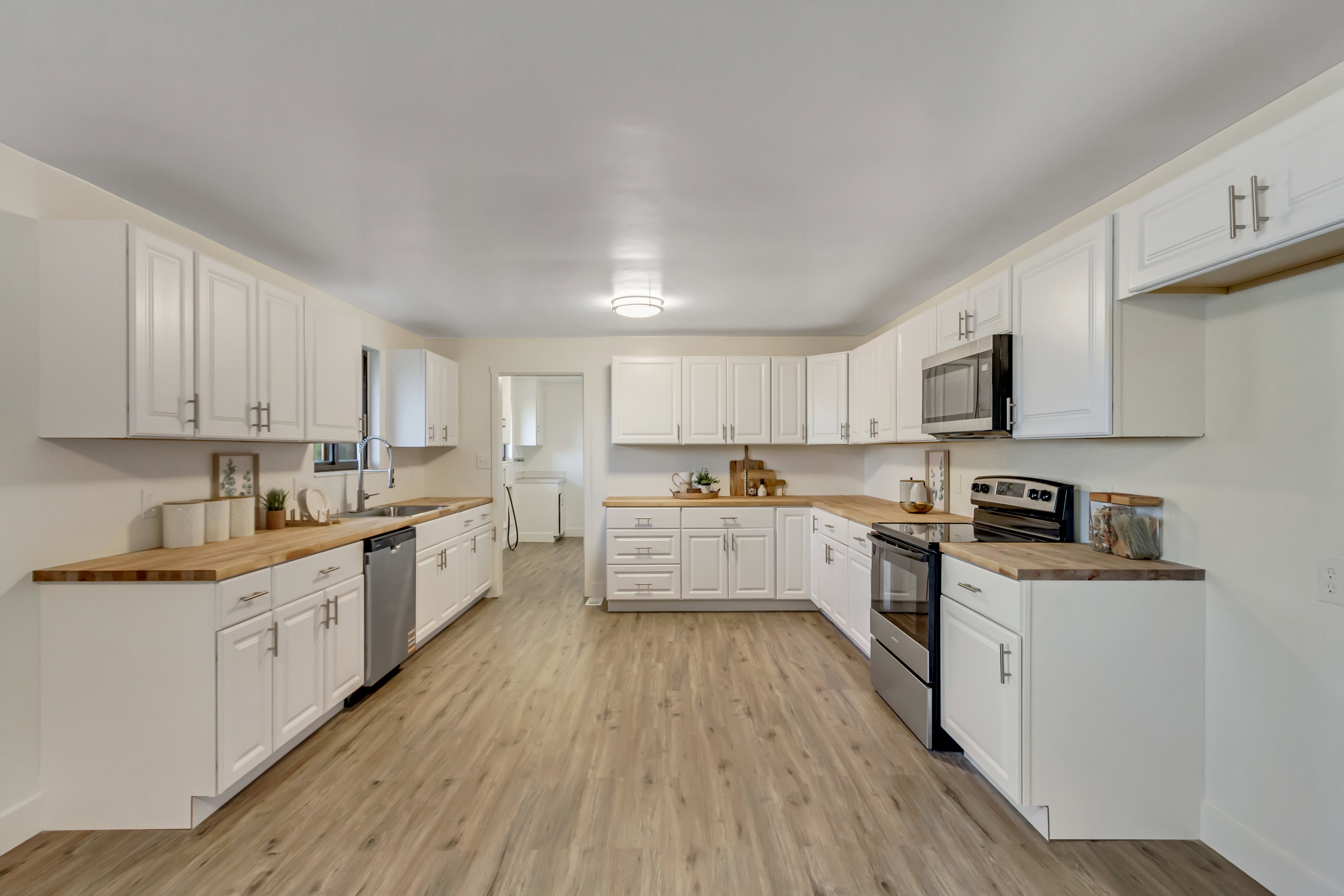 Kitchen featuring extensive white cabinetry, wood-finish countertops, stainless steel appliances, and wood-finish flooring