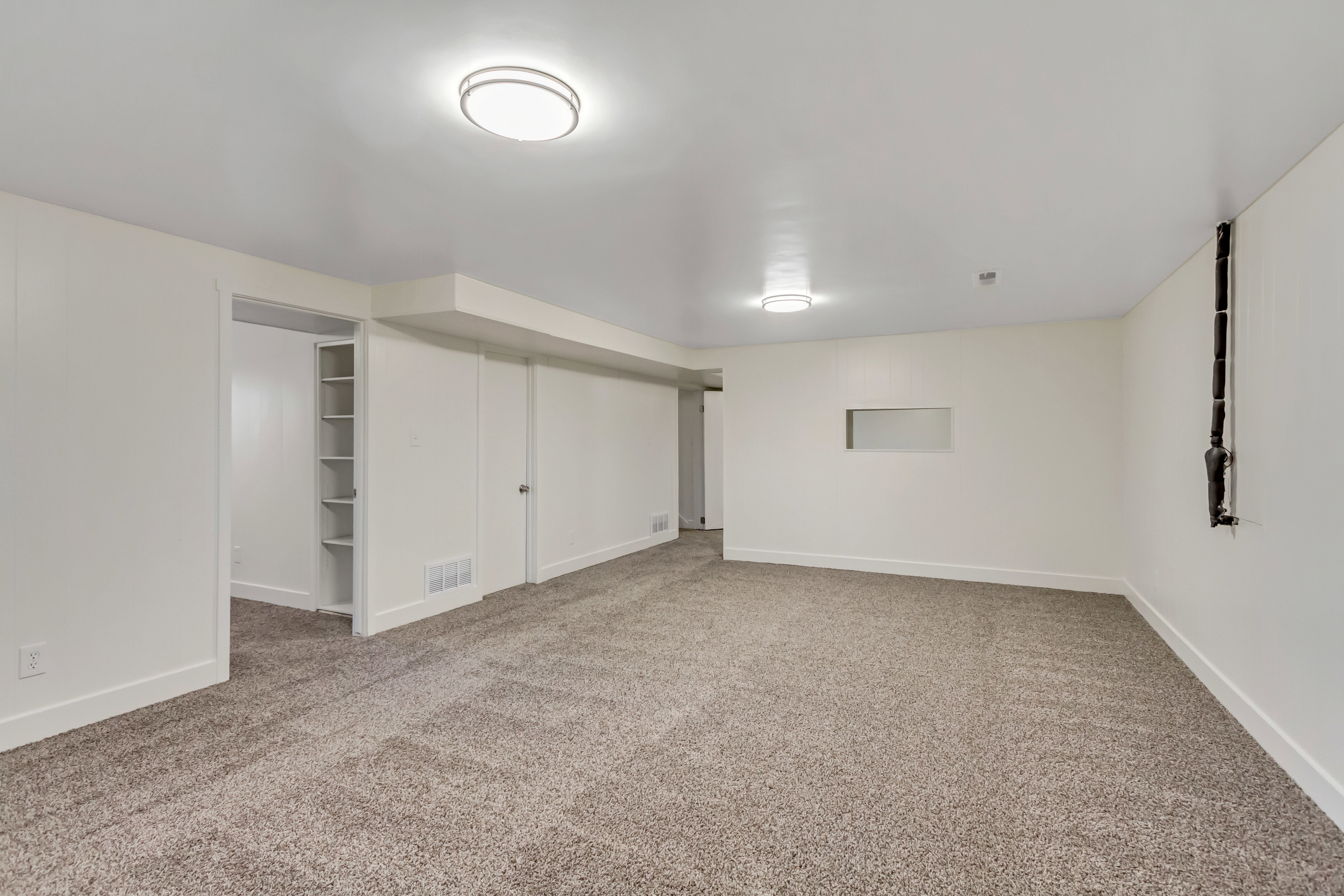 Spacious room featuring neutral carpeting, recessed lighting, and white walls