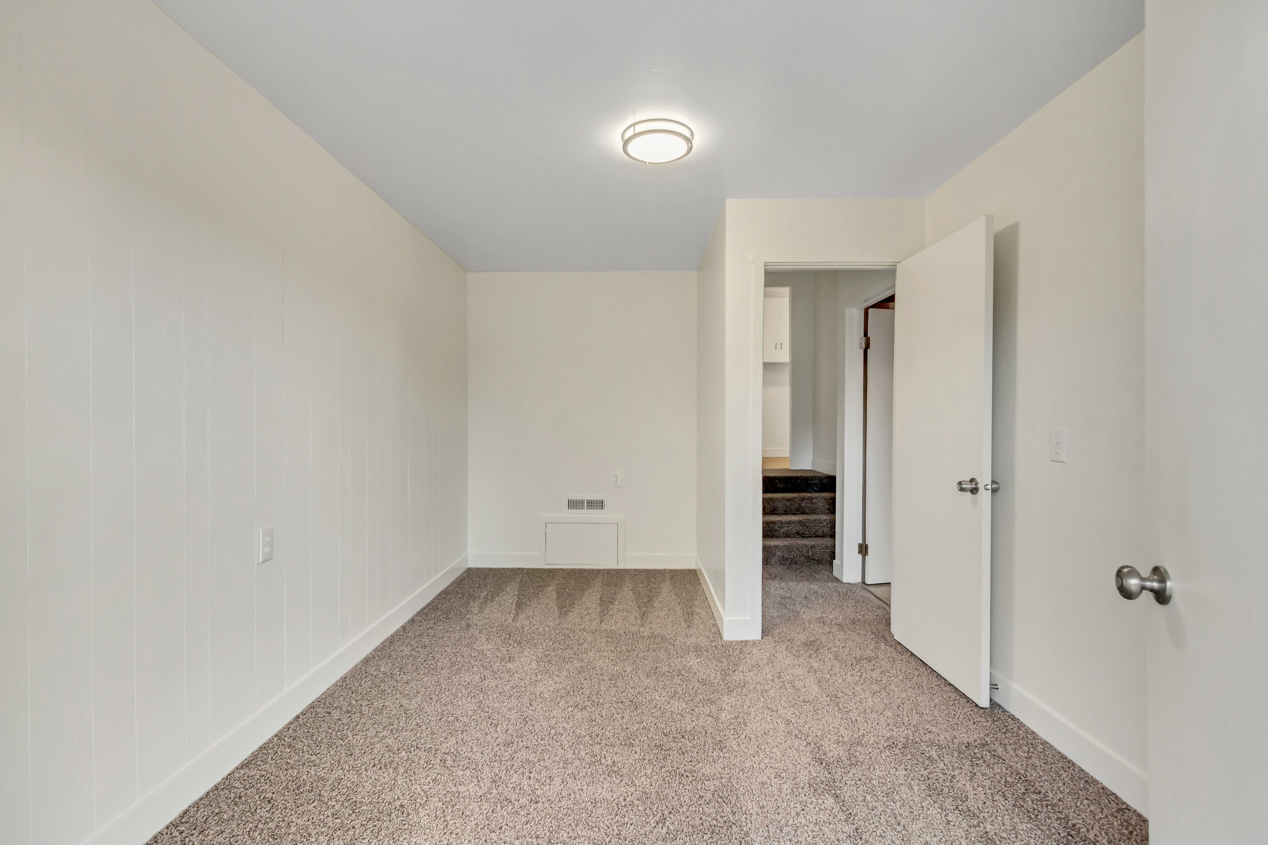 Neutral color palette room with light beige carpet flooring and white baseboards