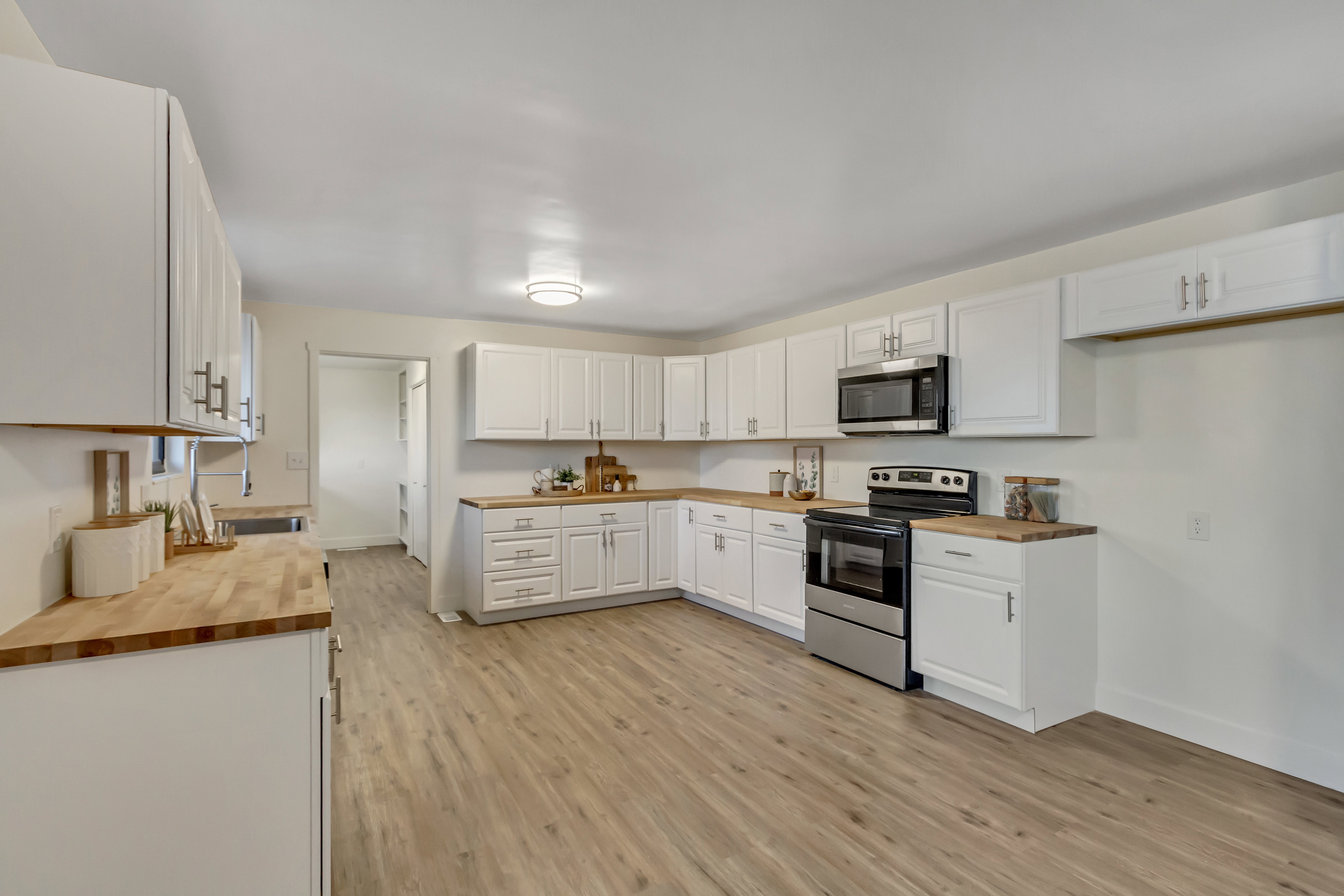 Kitchen featuring extensive white cabinetry, wood-finish countertops, stainless steel appliances, and wood-finish flooring