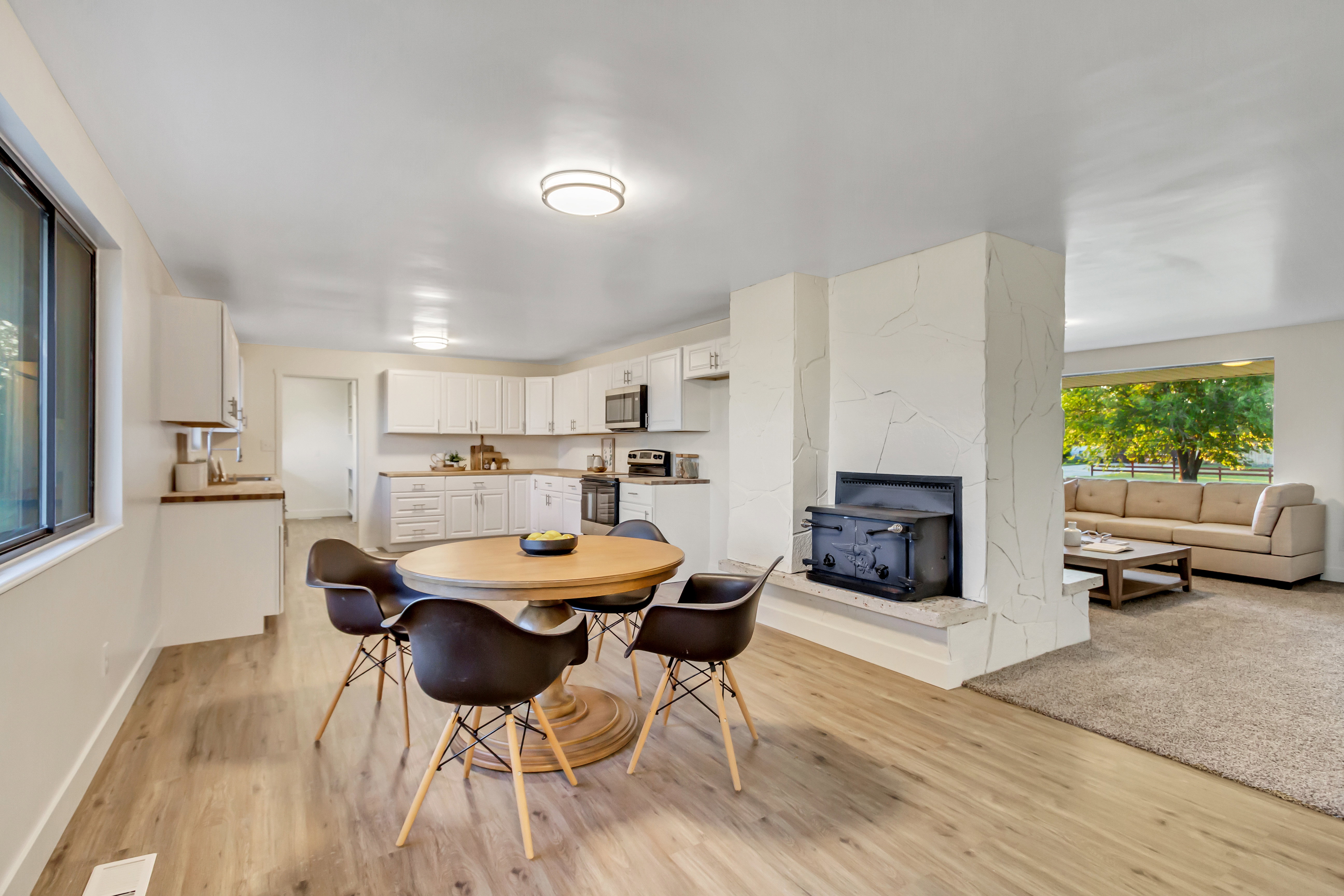 Open-concept living space featuring wood-finish flooring and a kitchen with white cabinetry and light countertops