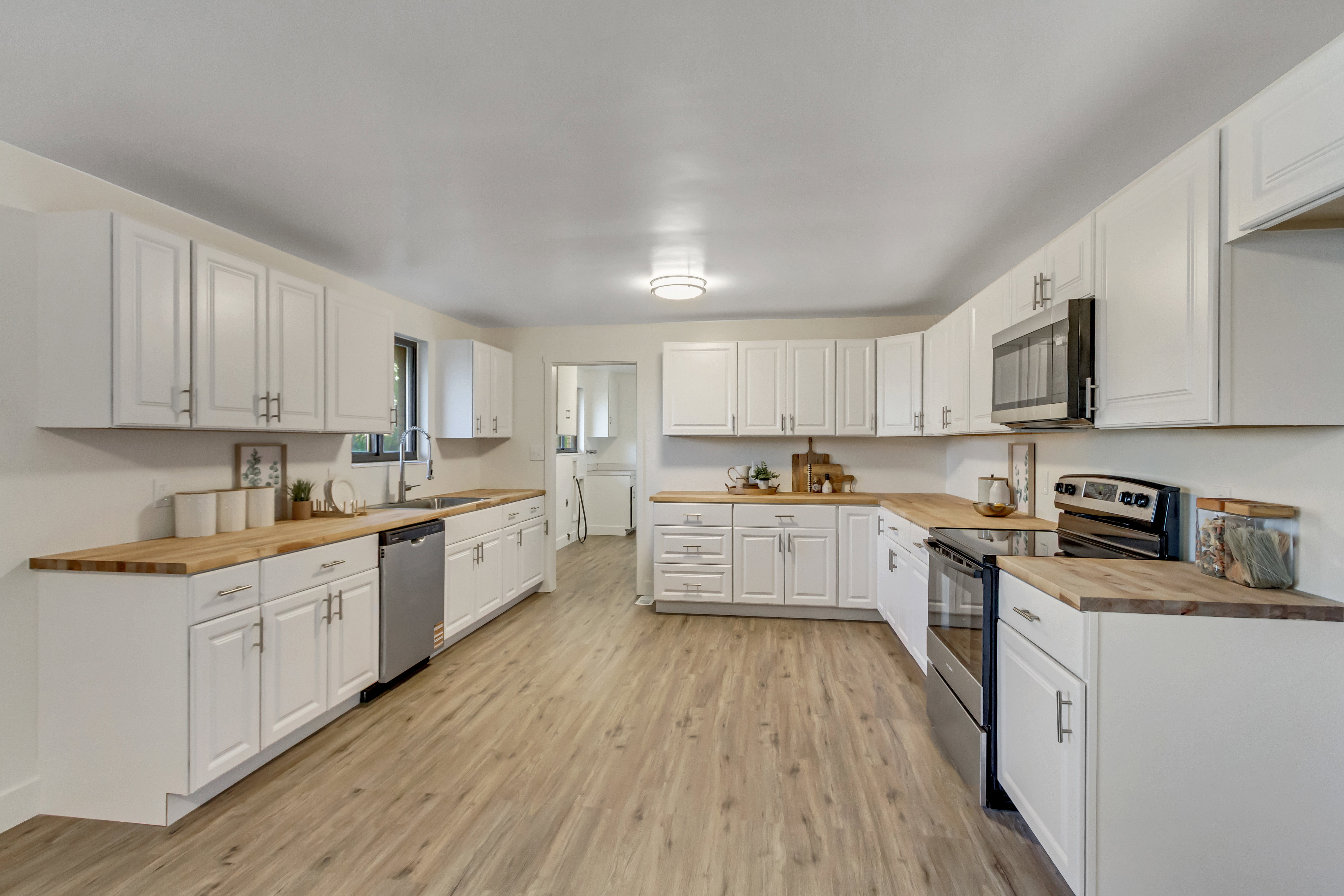 Spacious kitchen featuring extensive white cabinetry, wood-finish countertops, and wood-finish flooring