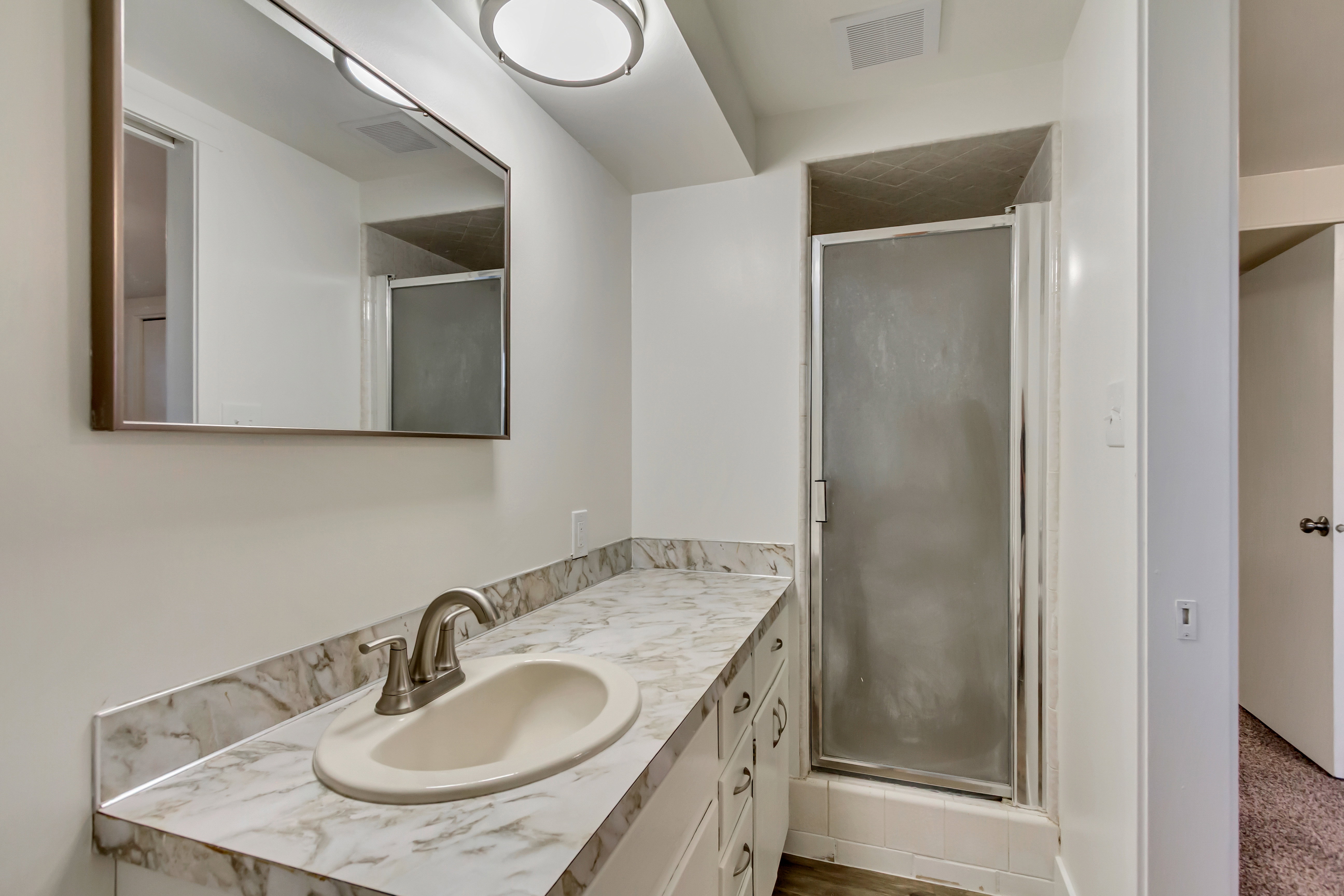 Bathroom featuring a single vanity with a laminate countertop, undermount sink, and brushed nickel faucet